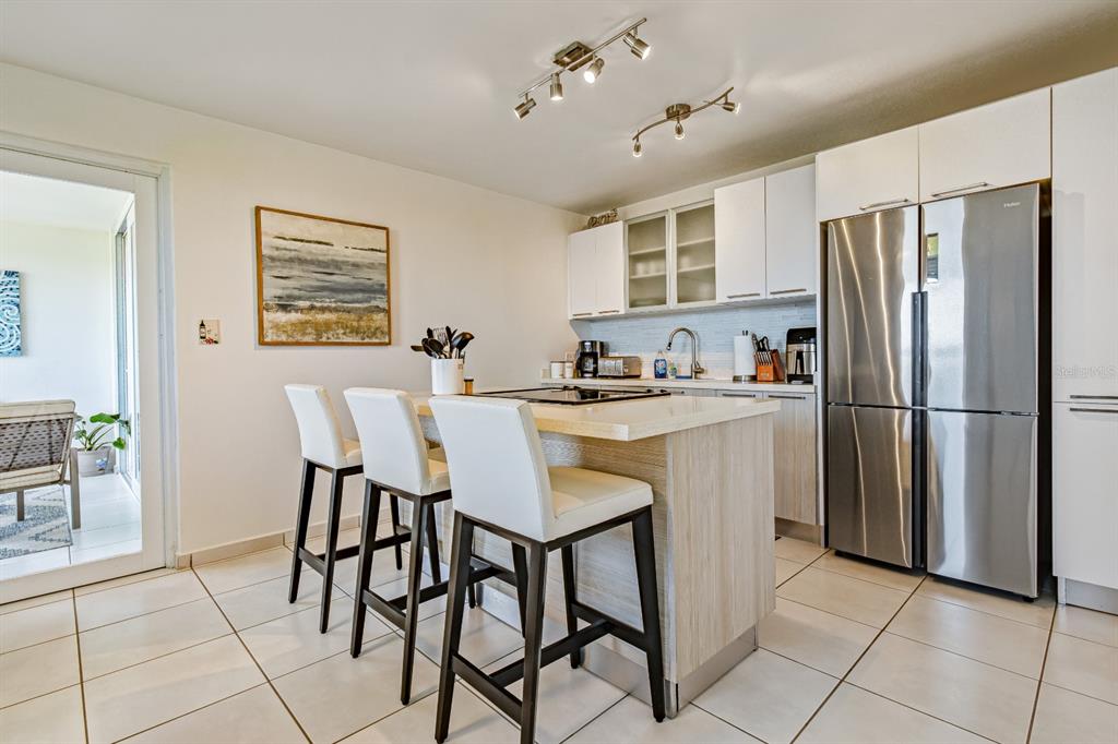 A kitchen features a central island with bar seating, white cabinetry, and stainless steel appliances — 100 OCEAN PLAZA DRIVE UNIT 15, LUQUILLO, PR