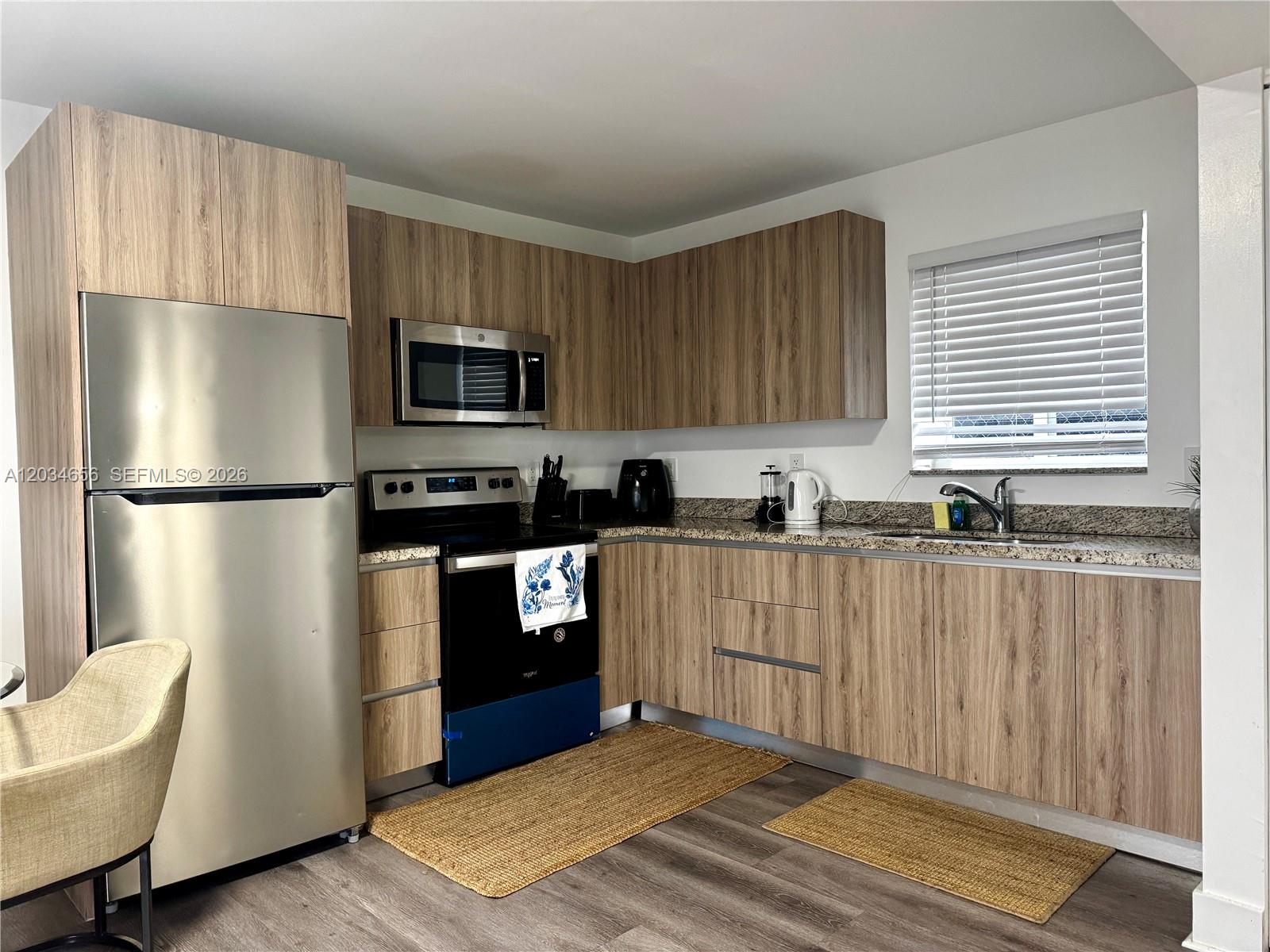 A kitchen features wood-grain cabinets, stainless steel appliances, and granite countertops — 1684 SW 10th St, Miami FL 33135, MIAMI, FL