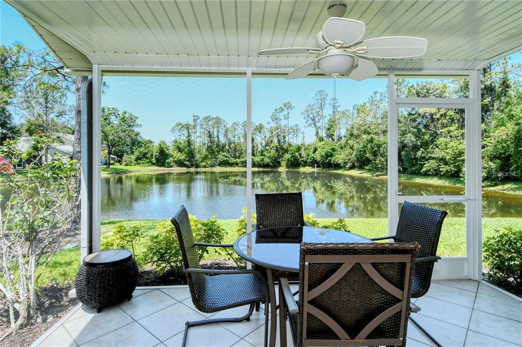 A screened-in patio with tile flooring, a ceiling fan, and a view of a pond — 5414 FAIR OAKS STREET UNIT 10-D, BRADENTON, FL