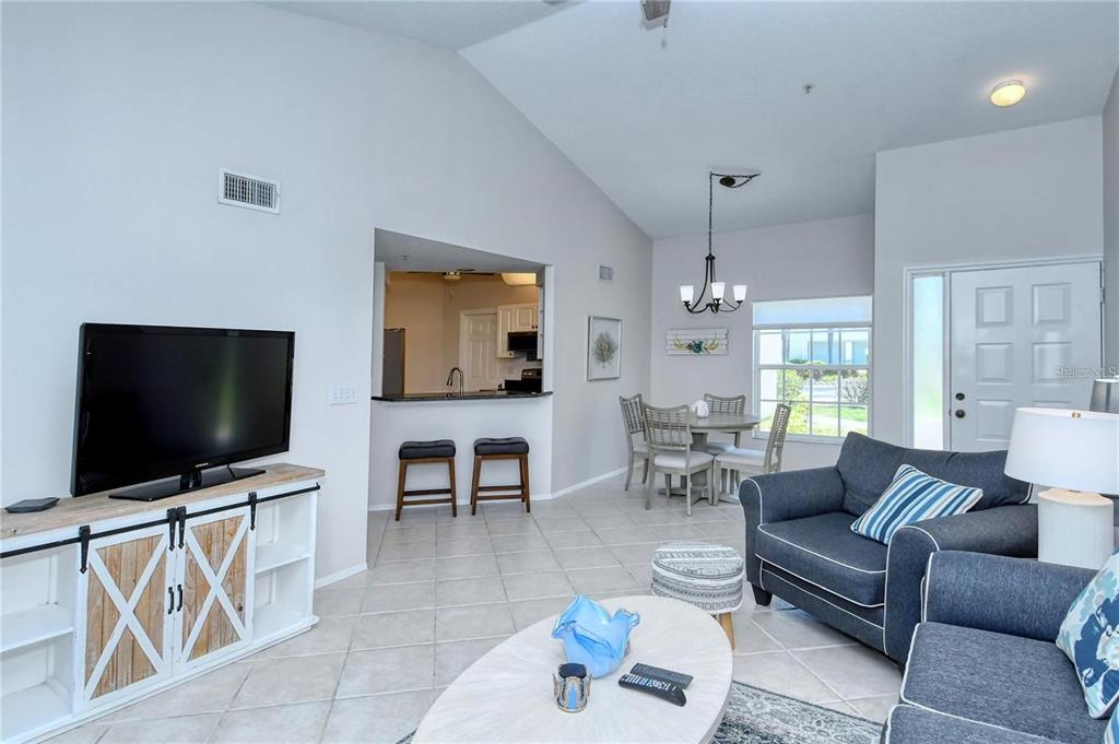 A living room with tile floors, a vaulted ceiling, and an open kitchen pass-through — 5414 FAIR OAKS STREET UNIT 10-D, BRADENTON, FL