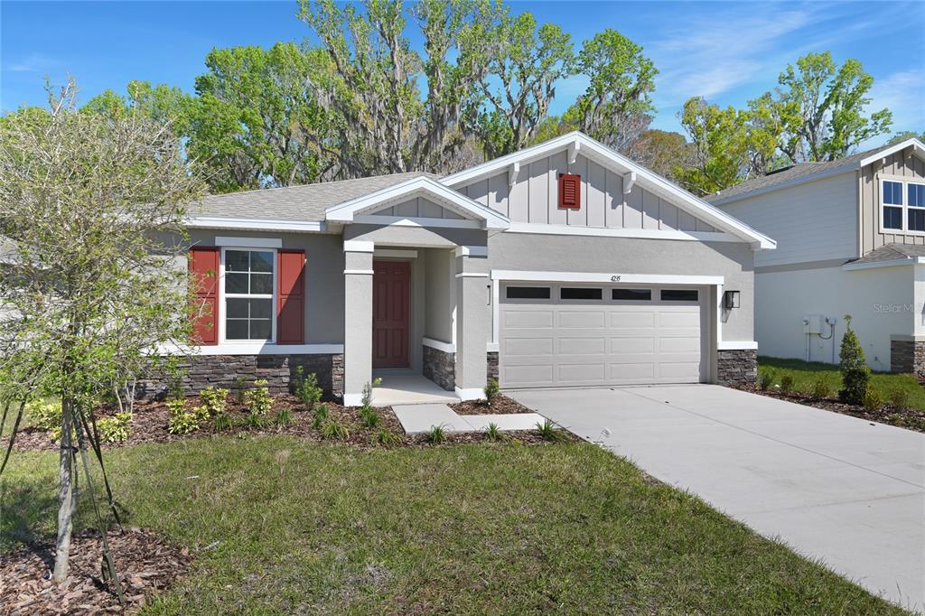 A single-story house with a gray stucco exterior, stone accents, and a two-car garage — 4235 SAWTOOTH COURT, TAVARES, FL