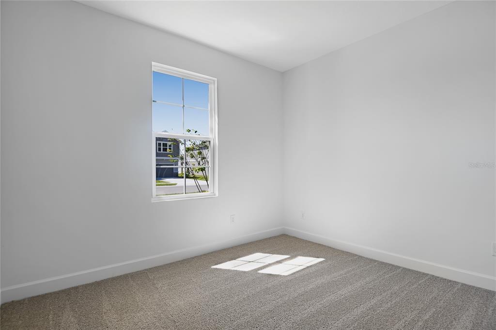 An empty bedroom features light gray walls, beige carpeting, and a single window — 4235 SAWTOOTH COURT, TAVARES, FL