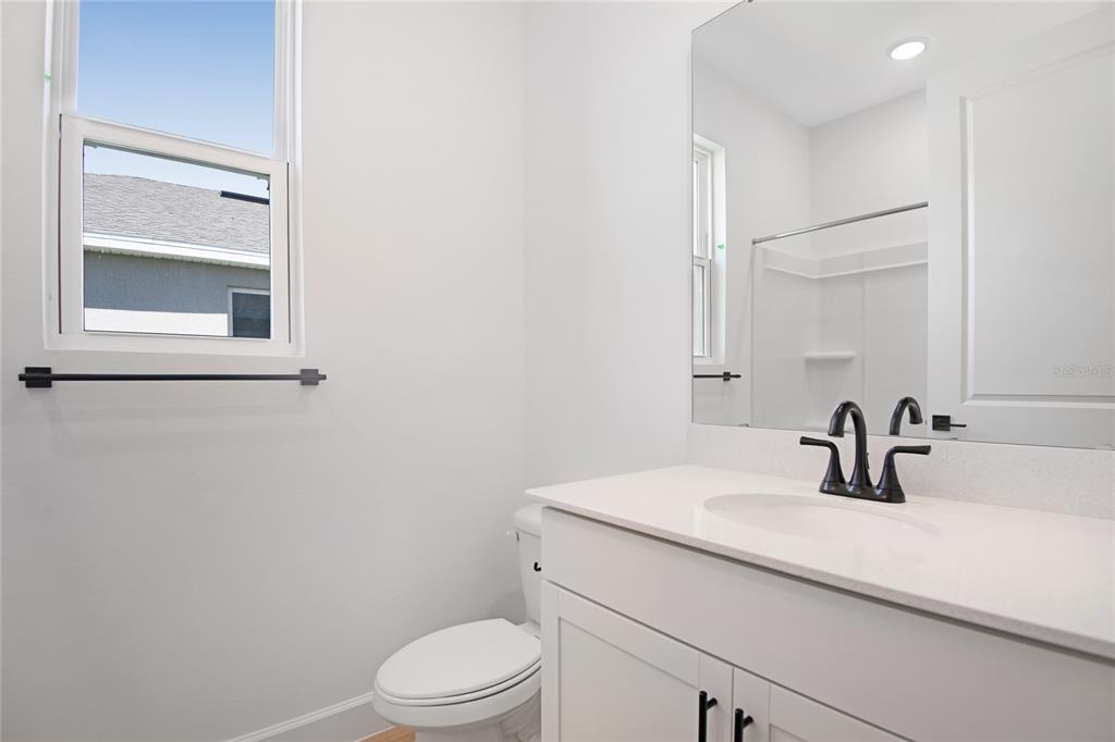 A bathroom features a white vanity with a dark faucet, a toilet, and a window — 4235 SAWTOOTH COURT, TAVARES, FL