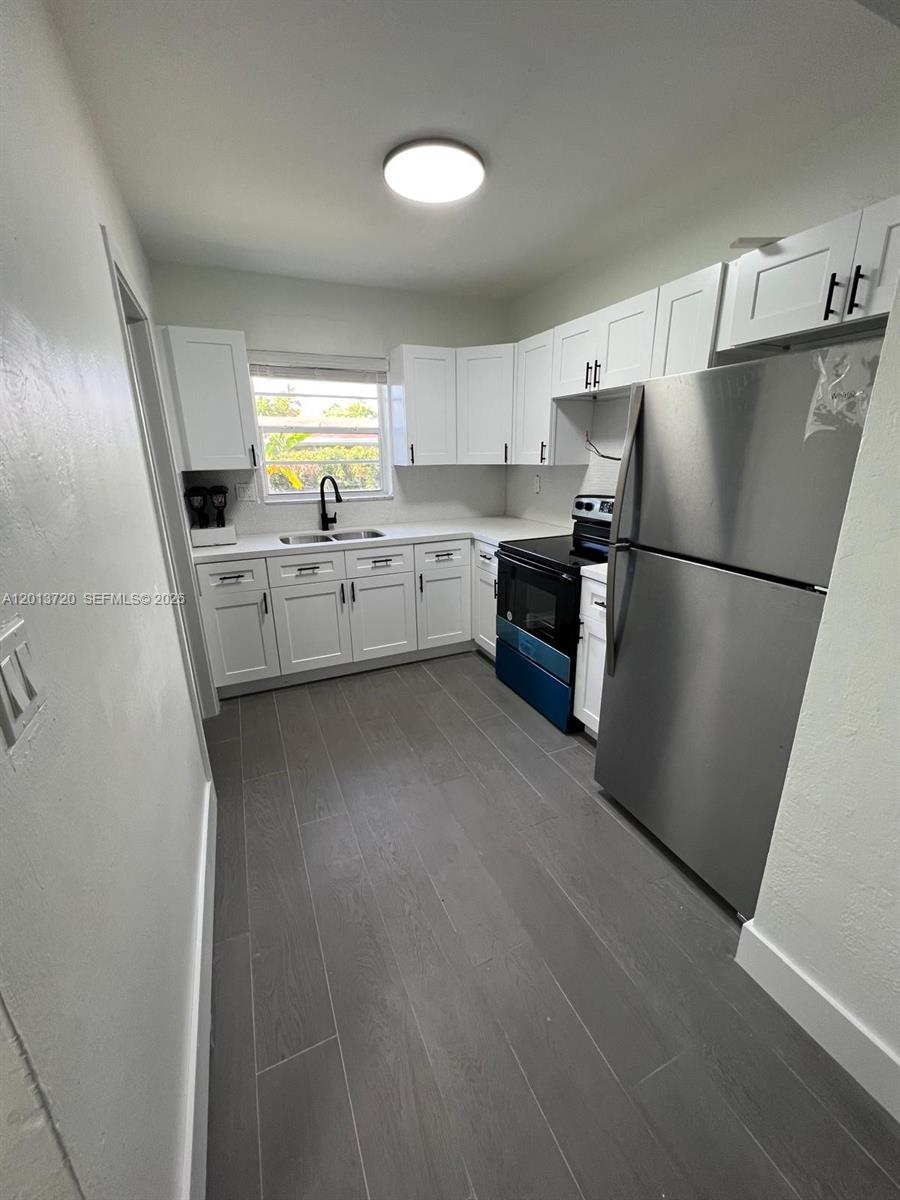 A kitchen features white cabinets, stainless steel appliances, and gray wood-look tile flooring — 2640 NE 215th St # 2640, Miami FL 33180, MIAMI, FL
