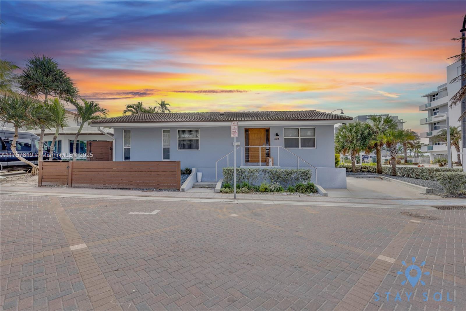 A single-story light blue house with a tiled roof sits behind a wooden fence — 328 Missouri St, Hollywood FL 33019, HOLLYWOOD, FL