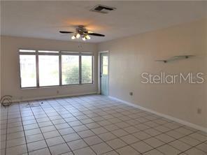 An empty room features white tiled floors, a ceiling fan, and a large window — 3621 MCINTOSH ROAD, SARASOTA, FL