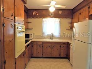 A kitchen with wood cabinets, a white refrigerator, a wall oven, and a window — 3621 MCINTOSH ROAD, SARASOTA, FL
