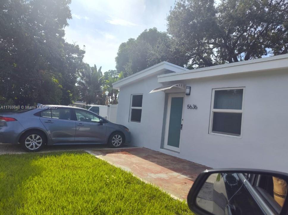 A white single-story house exterior features a front door, two windows, and a paved driveway — 5636 Arthur St, Hollywood FL 33021, HOLLYWOOD, FL
