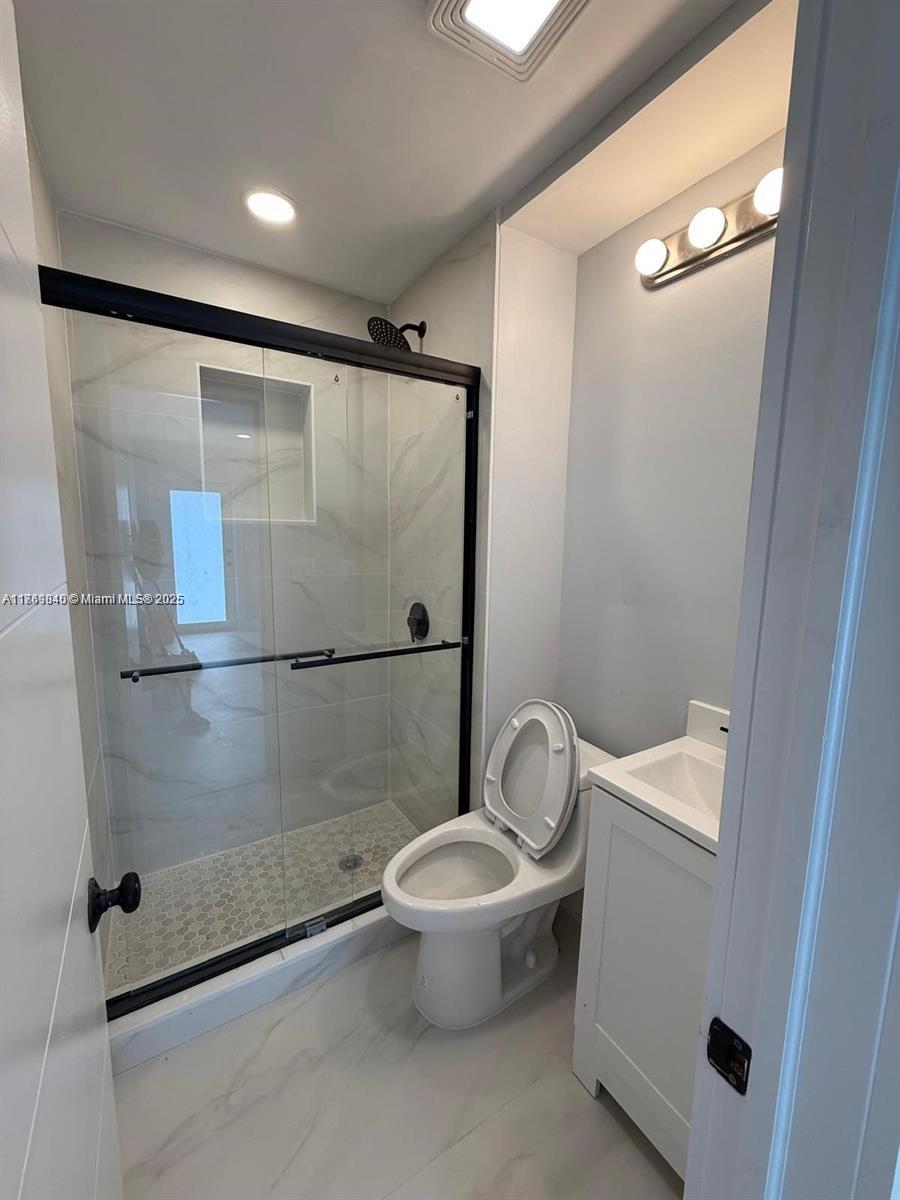 A small bathroom features a glass-enclosed shower, a white toilet, and a pedestal sink — 5636 Arthur St, Hollywood FL 33021, HOLLYWOOD, FL