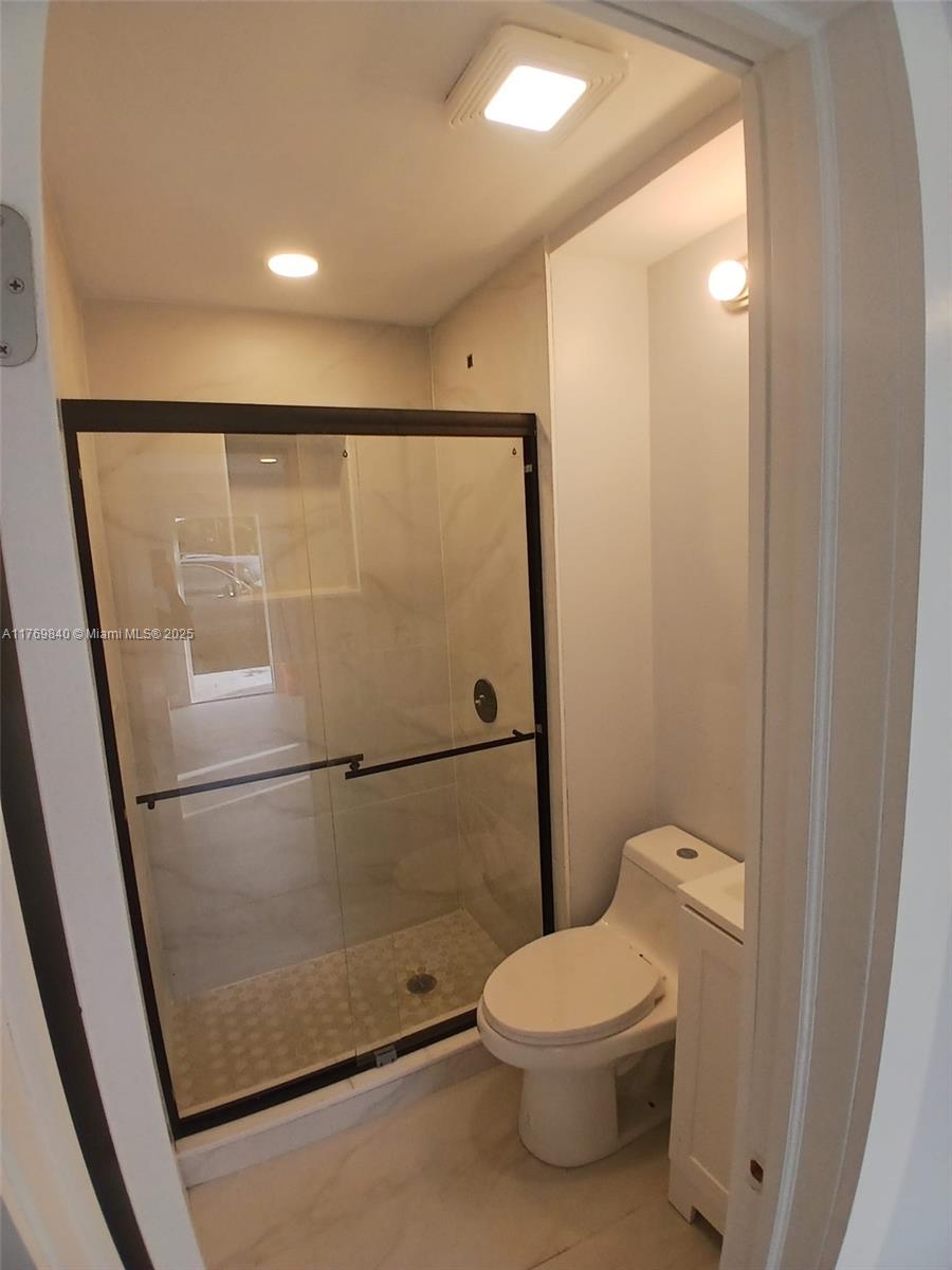 A small bathroom features a glass-enclosed shower with marble-look tile and a white toilet — 5636 Arthur St, Hollywood FL 33021, HOLLYWOOD, FL