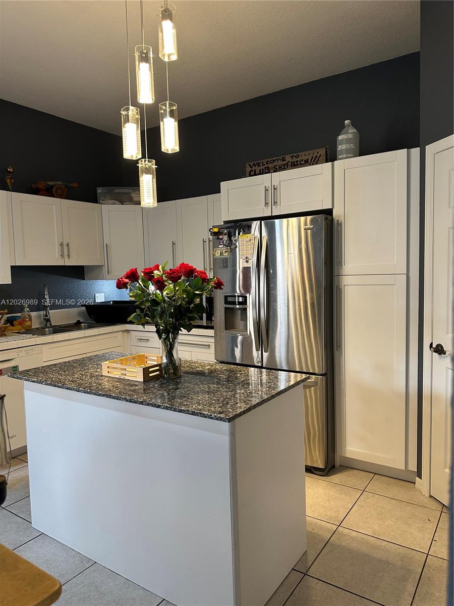A kitchen features white cabinets, a granite-topped island, stainless steel appliances, and pendant lighting — 1953 SE 24th Ave, Homestead FL 33035, HOMESTEAD, FL