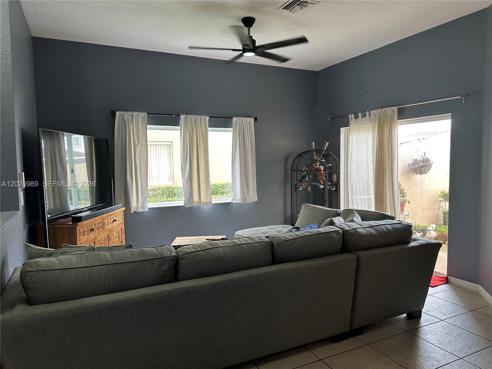 A living room features a large gray sectional sofa, a television, and a sliding glass door — 1953 SE 24th Ave, Homestead FL 33035, HOMESTEAD, FL