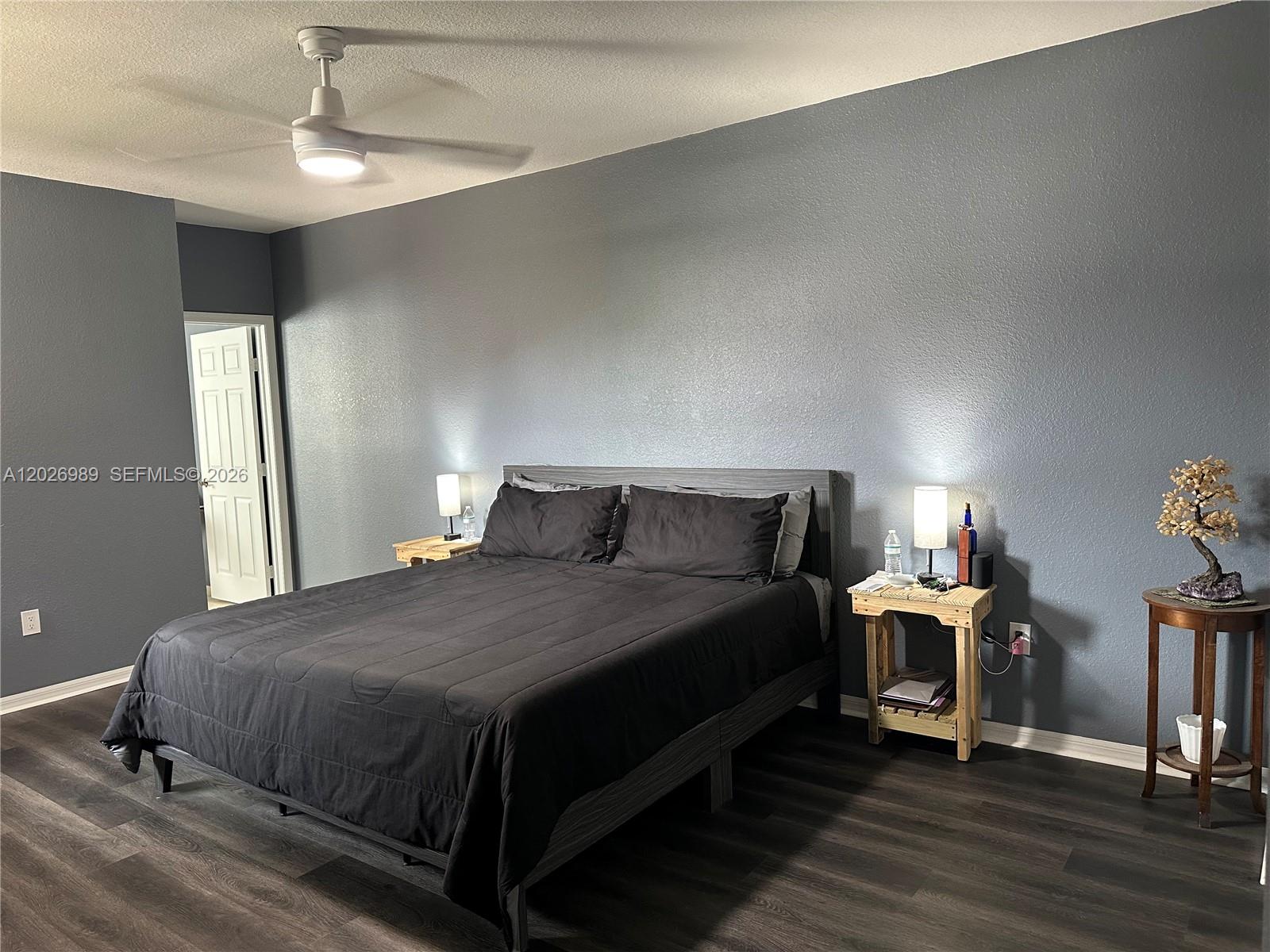 A bedroom features a dark gray accent wall, a bed with black bedding, and wood-toned flooring — 1953 SE 24th Ave, Homestead FL 33035, HOMESTEAD, FL
