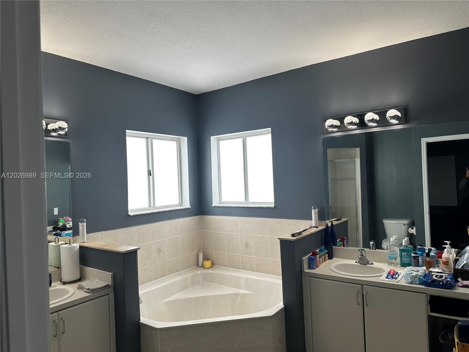 A bathroom features a corner soaking tub between two vanities with dark blue walls — 1953 SE 24th Ave, Homestead FL 33035, HOMESTEAD, FL