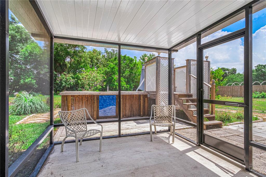 A screened-in patio features a concrete floor, two chairs, and an outdoor wooden bar area — 3545 PERKINS AVENUE, MOUNT DORA, FL