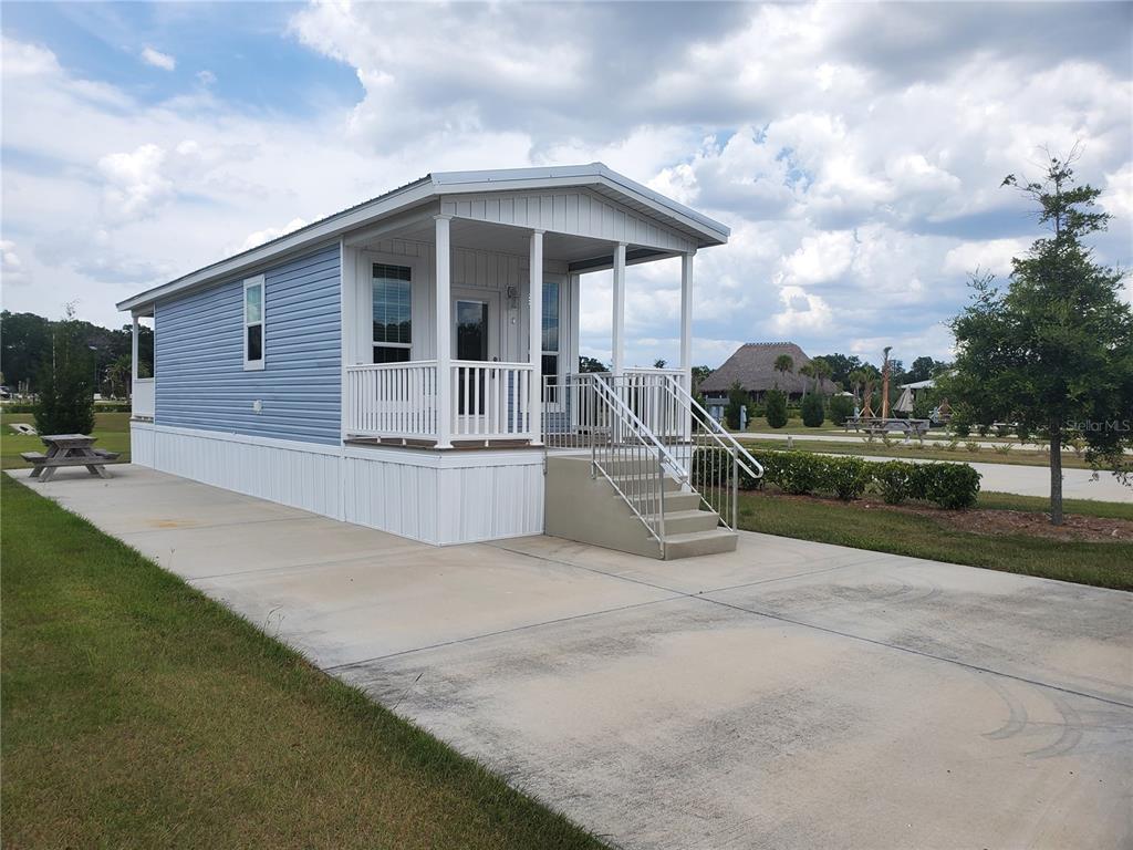 A light blue mobile home with a front porch sits on a concrete driveway — 4345 NW 27TH PLACE, OCALA, FL