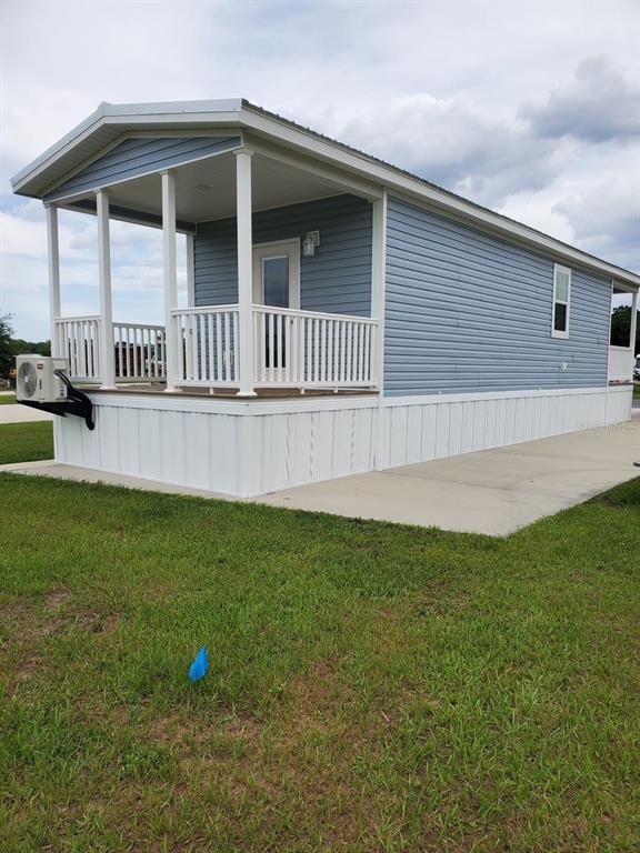 A light blue mobile home with a covered front porch and white skirting sits on grass — 4345 NW 27TH PLACE, OCALA, FL
