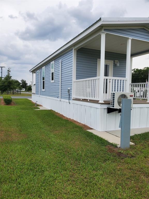 A blue vinyl-sided tiny home with a covered front porch and an outdoor AC unit — 4345 NW 27TH PLACE, OCALA, FL