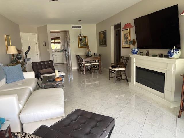 A living room with white tile floors, a fireplace, and a dining area in the background — 3 Garden Street # 203k, Tequesta FL 33469, TEQUESTA, FL