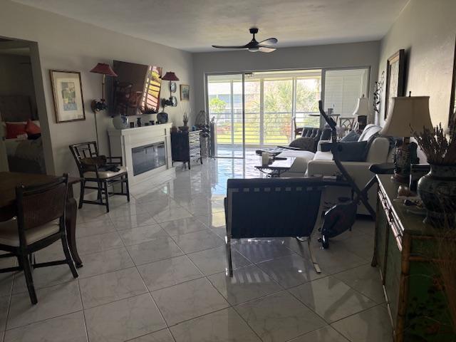 A living room with tile floors, a fireplace, and sliding glass doors leading to a balcony — 3 Garden Street # 203k, Tequesta FL 33469, TEQUESTA, FL