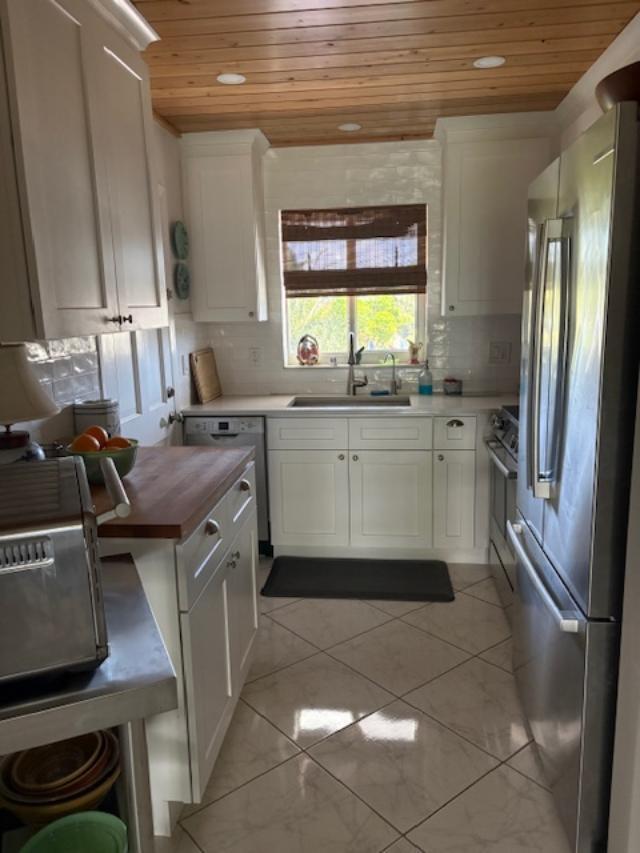 A galley kitchen features white cabinets, wood countertops, a stainless steel refrigerator, and wood-paneled ceiling — 3 Garden Street # 203k, Tequesta FL 33469, TEQUESTA, FL