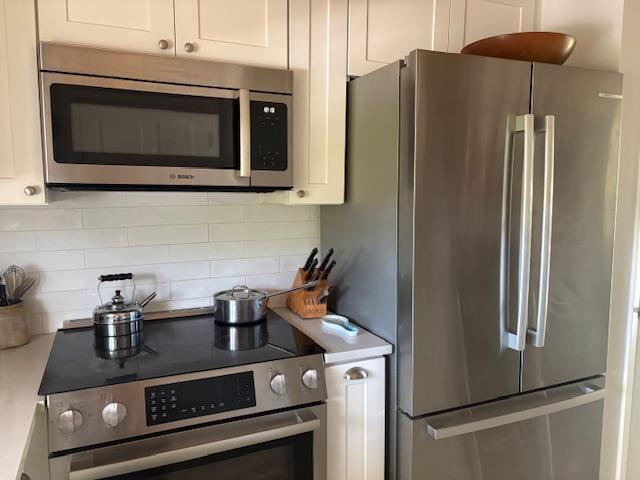 A kitchen features stainless steel appliances, white cabinets, and a white subway tile backsplash — 3 Garden Street # 203k, Tequesta FL 33469, TEQUESTA, FL