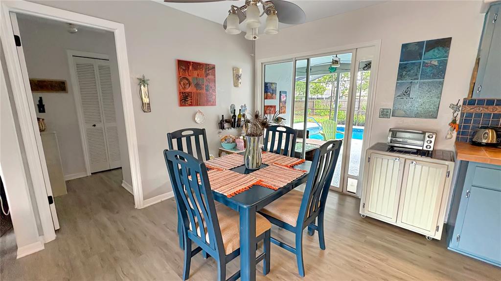 A dining area features a blue table and chairs, light flooring, and a sliding glass door — 1420 SOMERSET AVENUE, SPRING HILL, FL