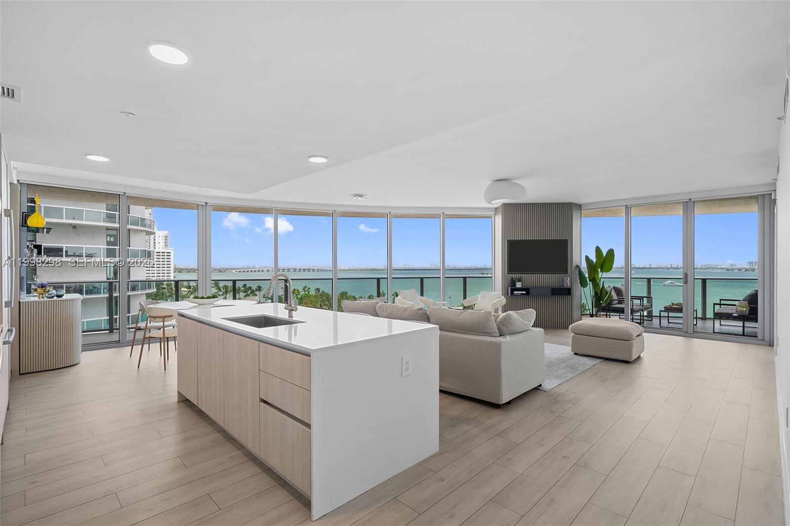 A modern open-concept living area features a kitchen island, light wood flooring, and floor-to-ceiling windows — 488 NE 18th St # 715, Miami FL 33132, MIAMI, FL