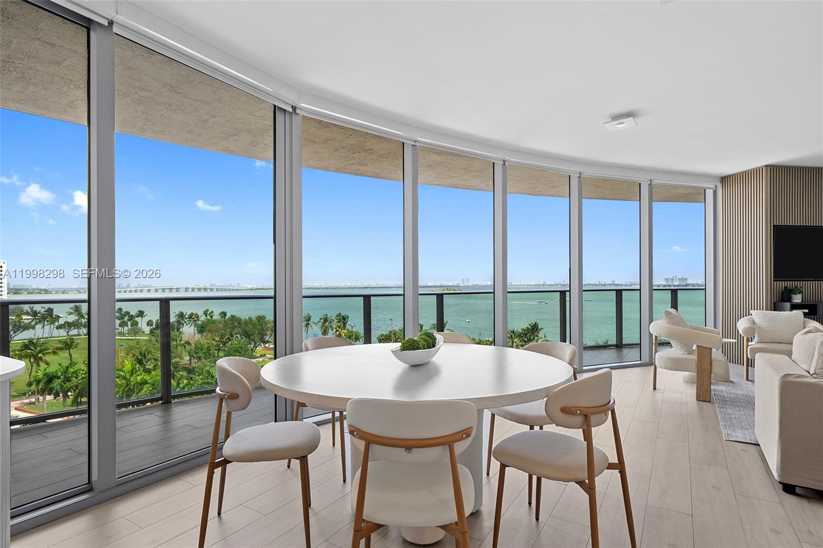 A dining area with a round table and floor-to-ceiling windows overlooking the water — 488 NE 18th St # 715, Miami FL 33132, MIAMI, FL