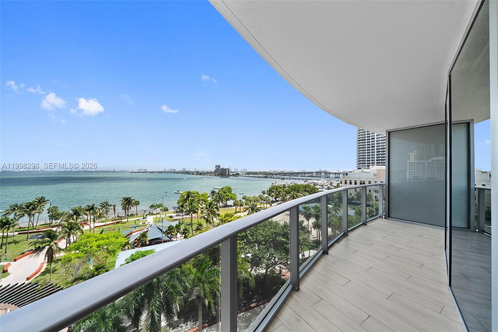 A high-rise balcony with glass railings overlooks a park, a bay, and a distant bridge — 488 NE 18th St # 715, Miami FL 33132, MIAMI, FL
