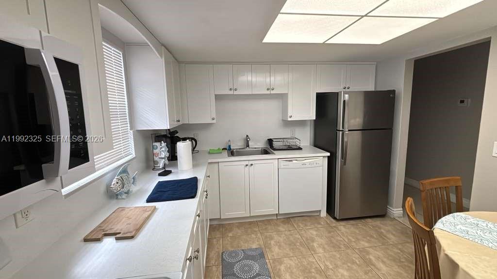 A kitchen features white cabinets, stainless steel appliances, and light-colored tile flooring — 1120 NE 24th Ave # 2, Pompano Beach FL 33062, POMPANO BEACH, FL