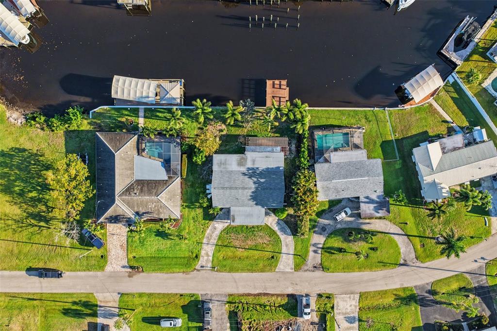 An aerial view shows three waterfront houses with pools, docks, and driveways along a canal — 468 GRENIER DRIVE, NORTH FORT MYERS, FL