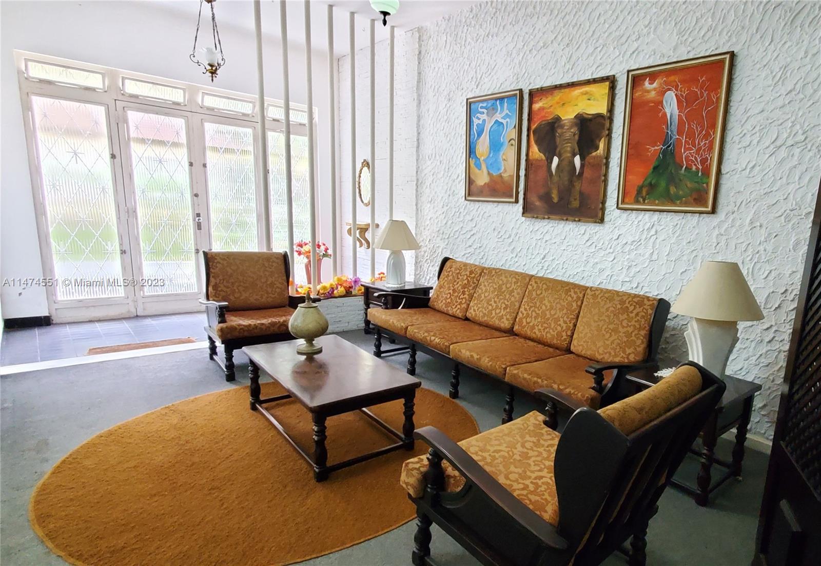 A living room features a patterned sofa and chairs, a coffee table, and three wall paintings — 311 MOSELA, FL 25675-481, FL