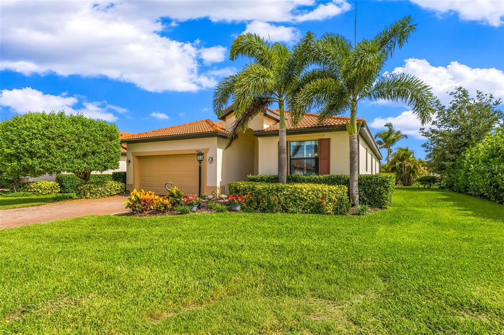A single-story house with a tan exterior, tile roof, and palm trees in the front yard — 10233 LOCH LOMOND DRIVE, BRADENTON, FL