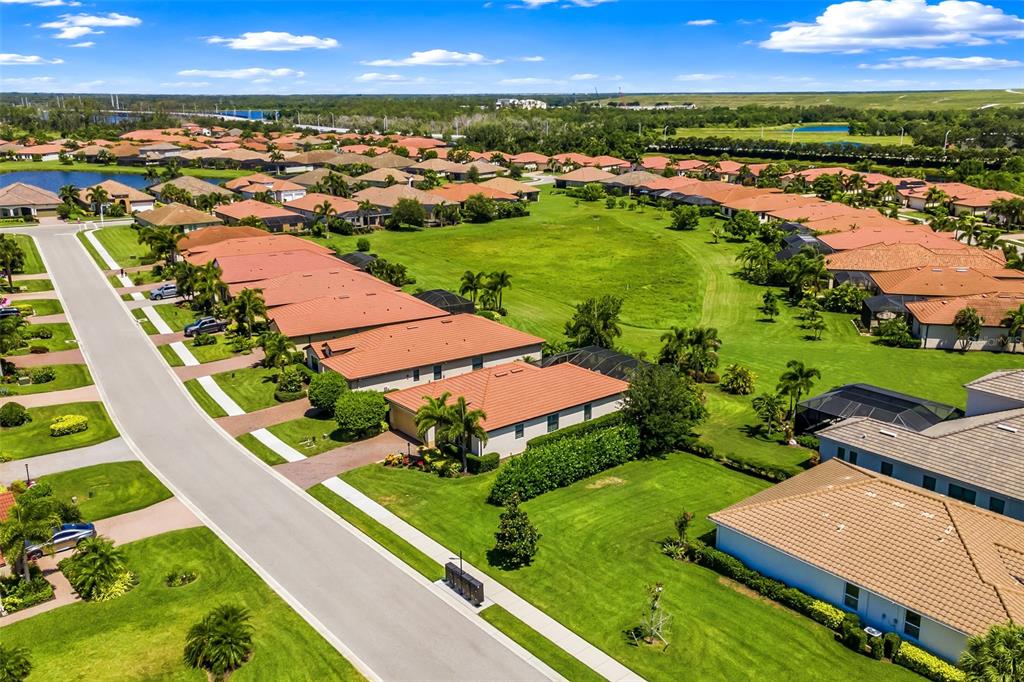 An aerial view shows a suburban neighborhood with rows of houses featuring terracotta-tiled roofs — 10233 LOCH LOMOND DRIVE, BRADENTON, FL