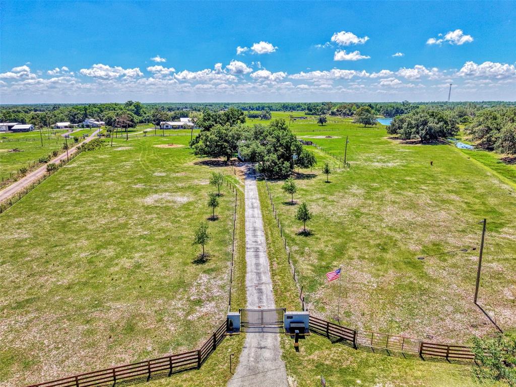 An aerial view shows a long driveway leading to a house surrounded by large trees — 10433 SW JERNIGAN STREET, ARCADIA, FL