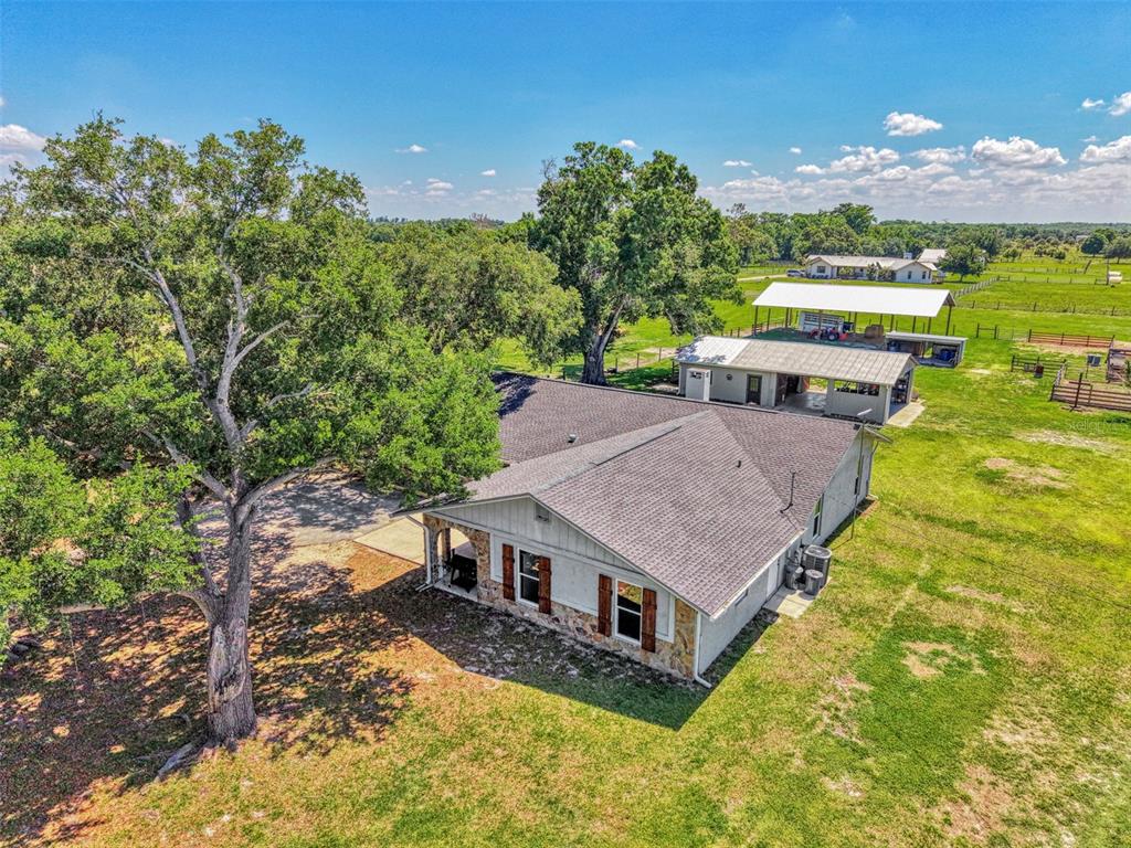 An aerial view shows a single-story house with a stone facade and an adjacent carport — 10433 SW JERNIGAN STREET, ARCADIA, FL