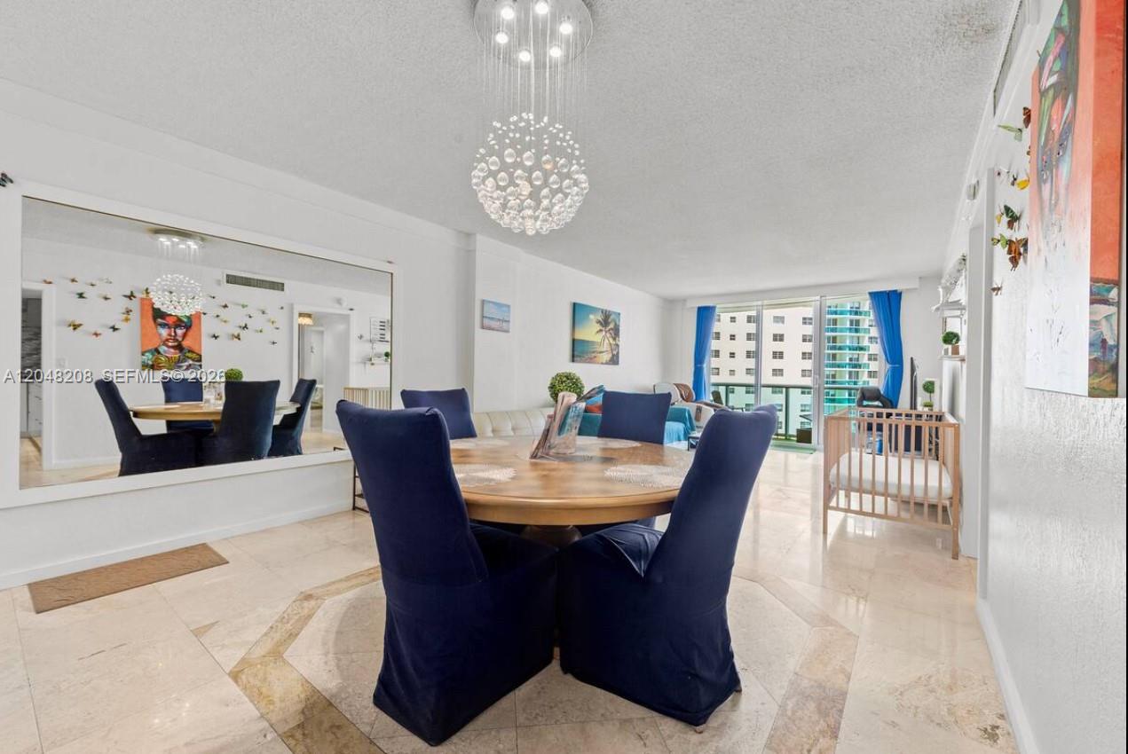 A dining area features a round wooden table with blue chairs and a crystal chandelier — 3901 S Ocean Dr # 9B, Hollywood FL 33019, HOLLYWOOD, FL