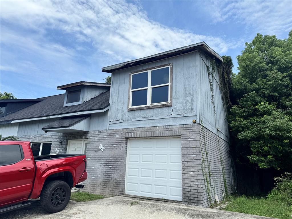 A two-story house with a brick lower level, gray siding, and a white garage door — 717 GASPARINO COURT, SEFFNER, FL