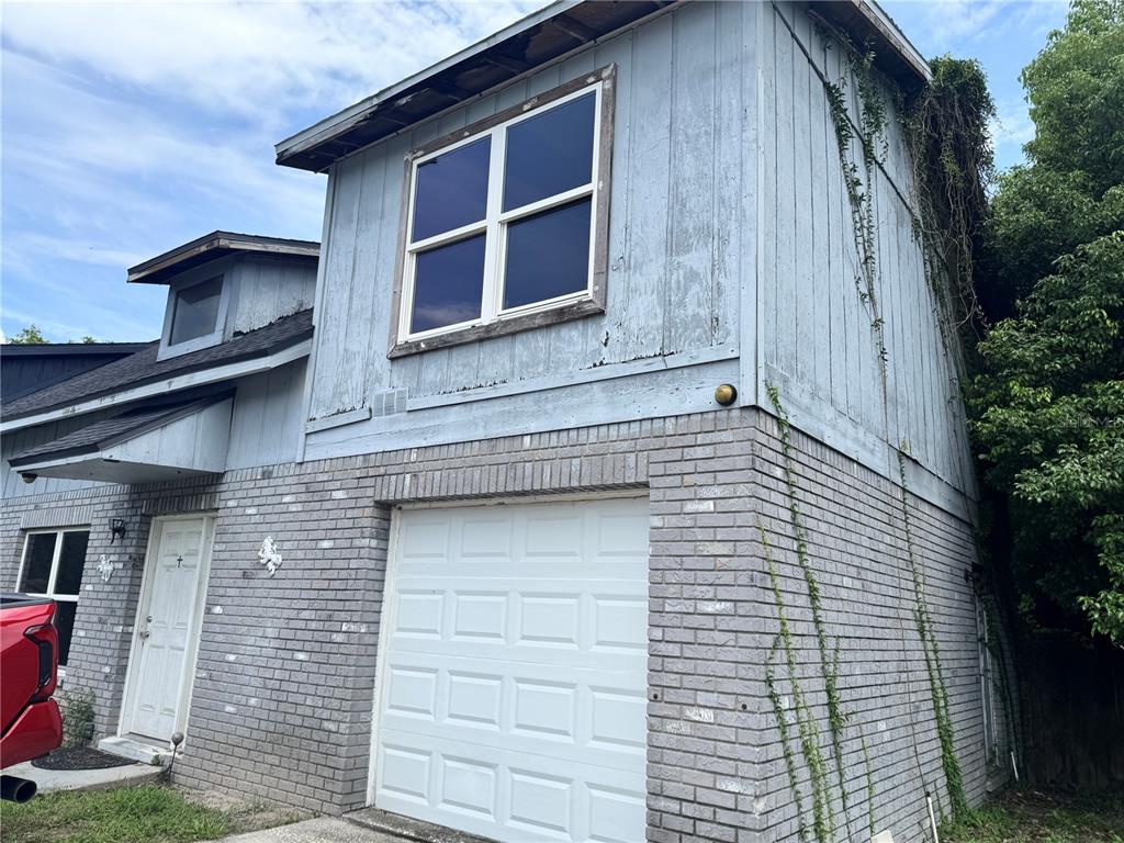 A two-story house exterior features a brick lower level, a garage, and blue wood siding — 717 GASPARINO COURT, SEFFNER, FL
