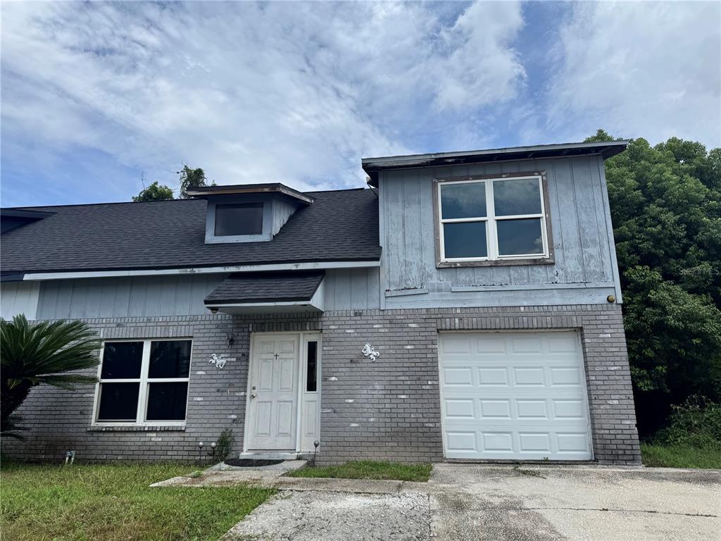A two-story house with a gray brick lower level, blue siding, and an attached garage — 717 GASPARINO COURT, SEFFNER, FL