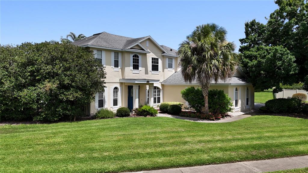 A two-story house with a beige exterior, a palm tree, and a grassy front yard — 10221 LUNDY COURT, ORLANDO, FL