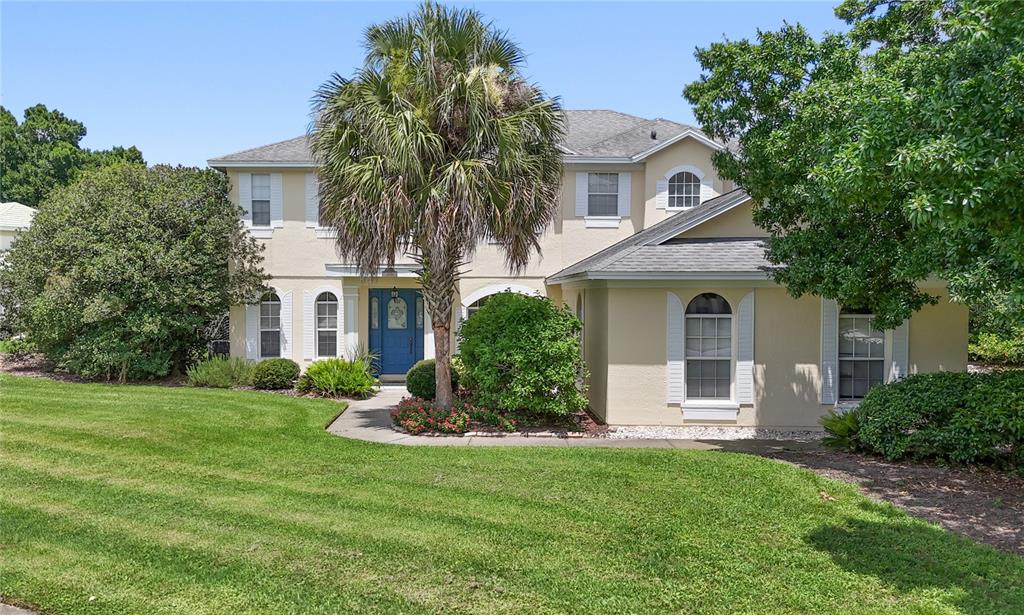 A two-story, light-colored house with a blue front door and a prominent palm tree — 10221 LUNDY COURT, ORLANDO, FL