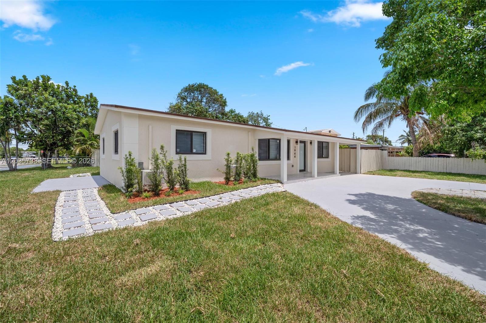 A single-story house with a beige exterior, a concrete driveway, and a stone walkway — 1944 NE 2nd Ave, Pompano Beach FL 33060, POMPANO BEACH, FL