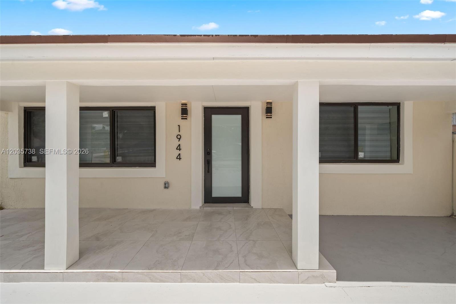 A covered front porch features tiled flooring, a modern glass-paneled door, and two white columns — 1944 NE 2nd Ave, Pompano Beach FL 33060, POMPANO BEACH, FL