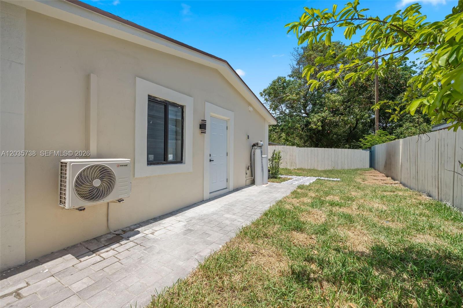 The exterior of a house features a paved walkway, a white door, and an AC unit — 1944 NE 2nd Ave, Pompano Beach FL 33060, POMPANO BEACH, FL