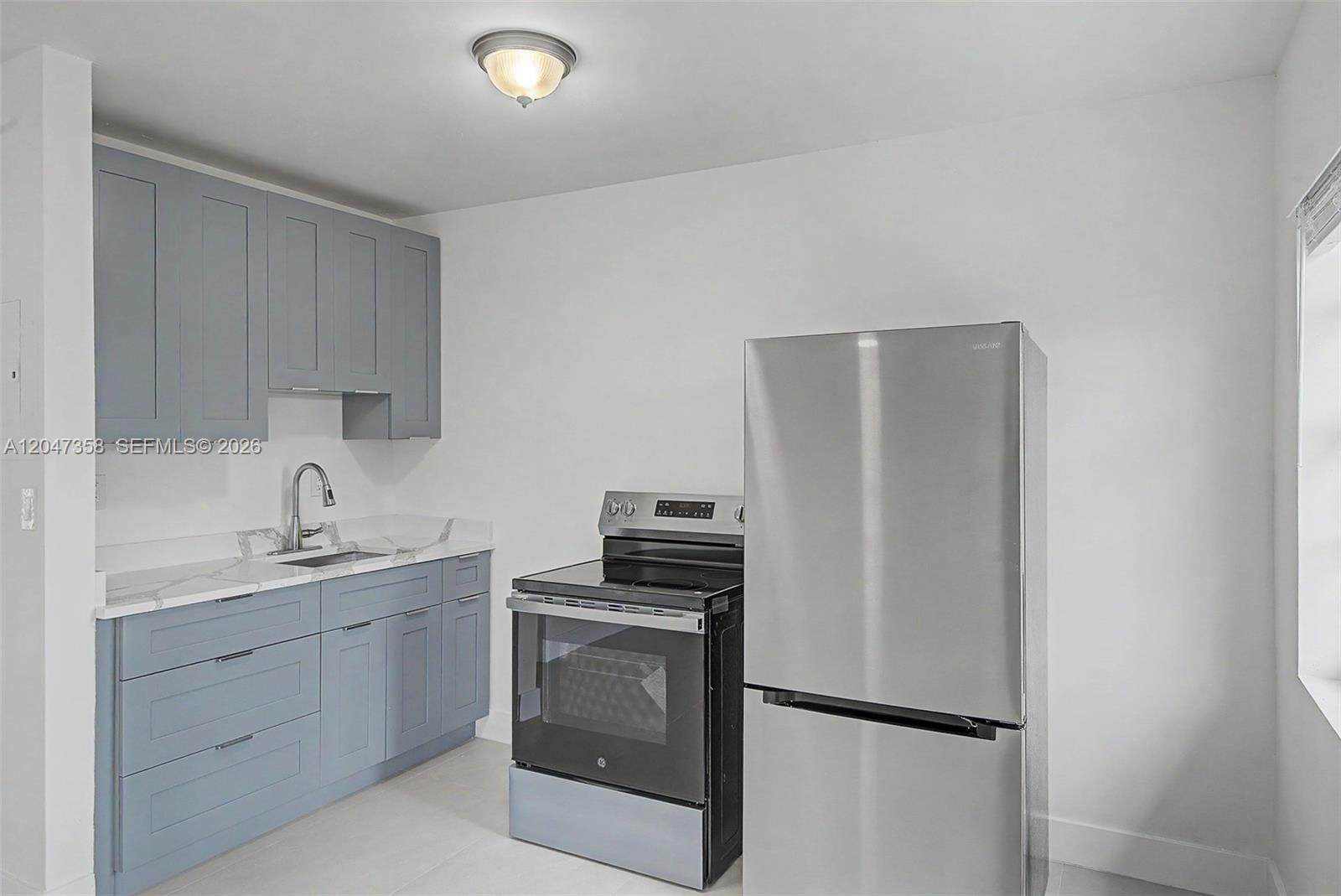 A kitchen features blue cabinets, white countertops, stainless steel appliances, and a ceiling light — 1021 SW 3rd St # 6, Miami FL 33130, MIAMI, FL