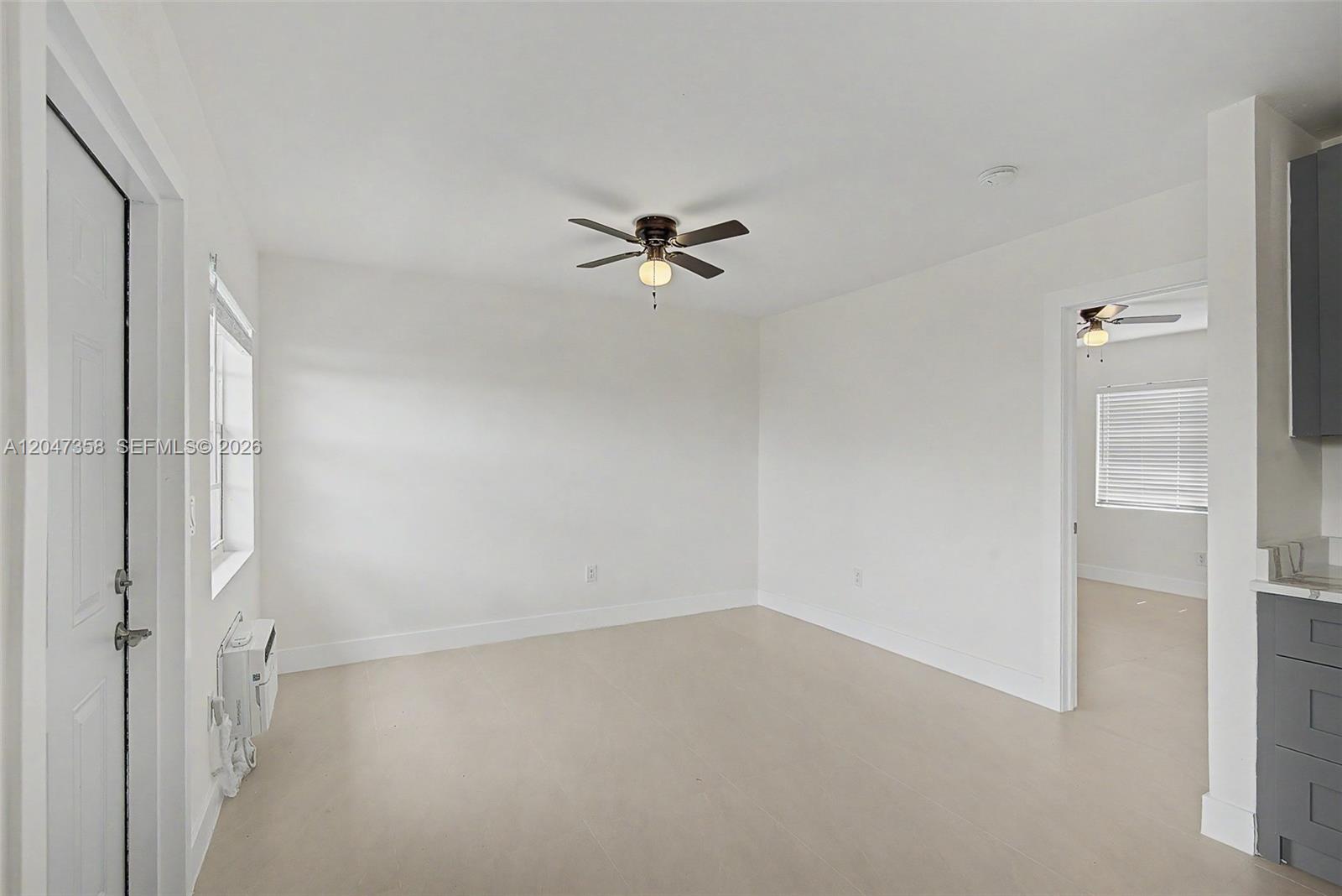 An empty room features white walls, light-colored tile flooring, a ceiling fan, and a window — 1021 SW 3rd St # 6, Miami FL 33130, MIAMI, FL