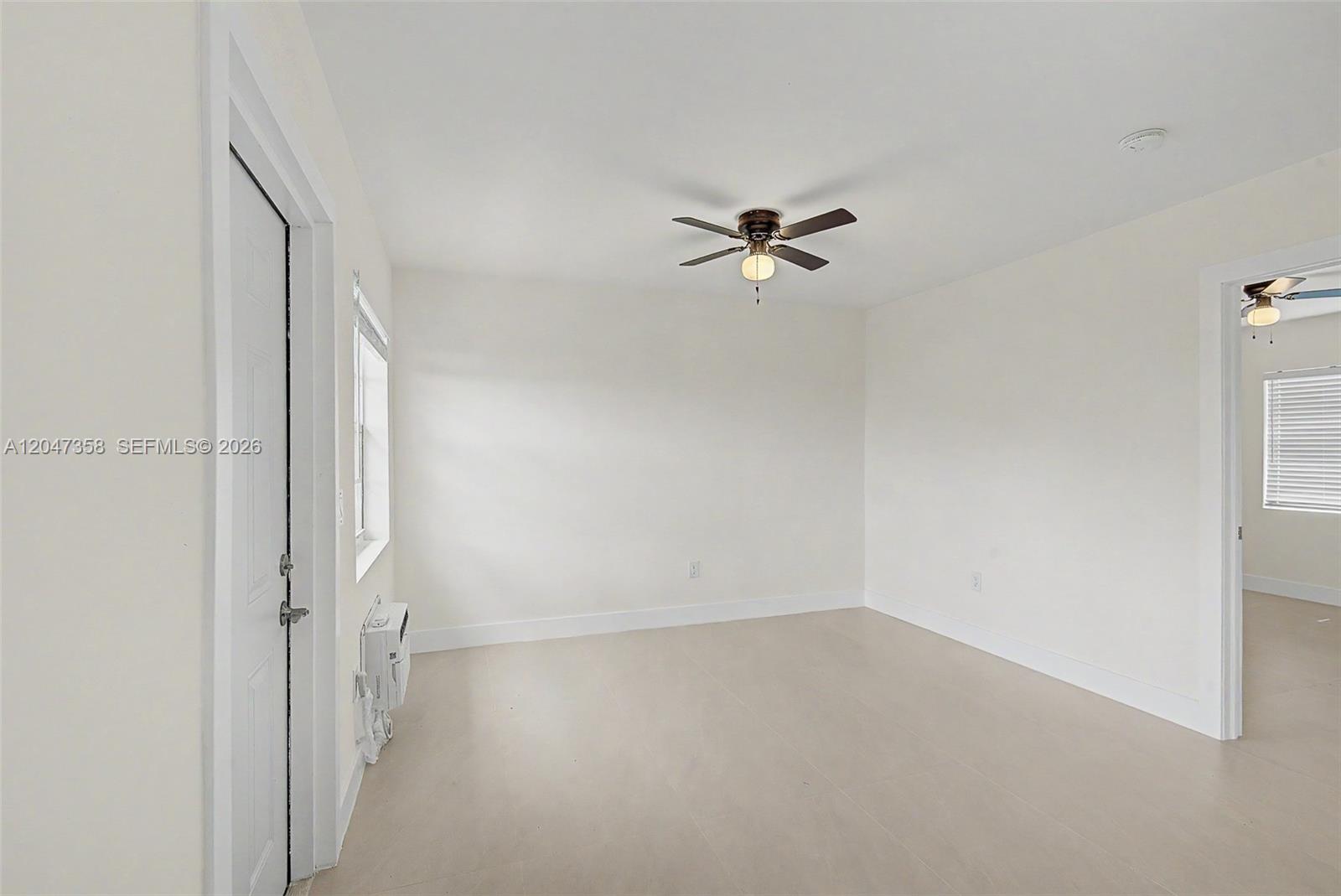 A bright, empty room features white walls, light-colored flooring, a ceiling fan, and a window — 1021 SW 3rd St # 6, Miami FL 33130, MIAMI, FL