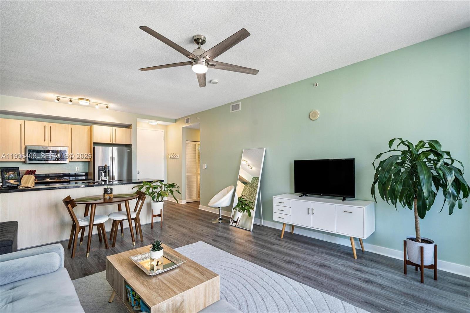 A living room and kitchen area features light green walls, wood flooring, and modern furniture — 1111 SW 1st Ave, Miami FL 33130, MIAMI, FL